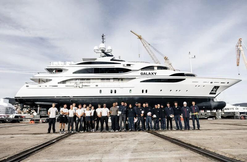 a group of people standing in front of a large ship aboard GALAXY Yacht for Sale