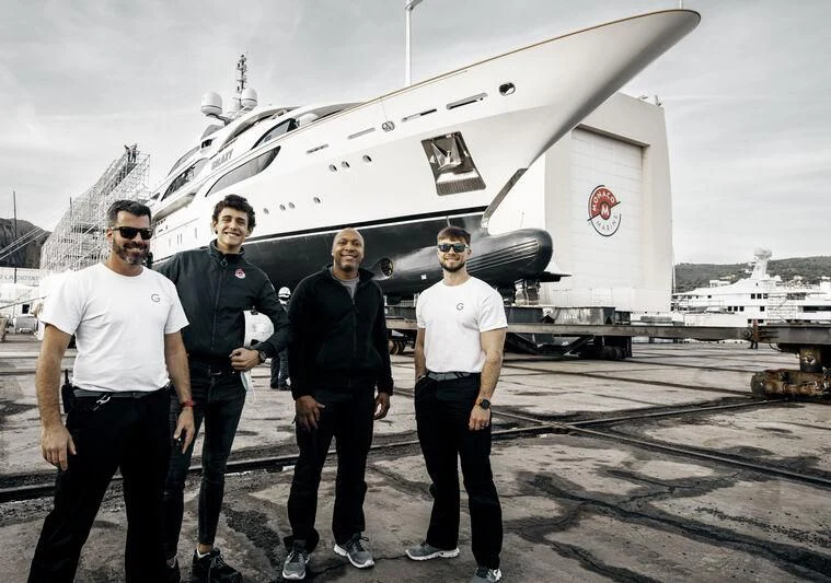a group of men posing for a photo in front of a plane aboard GALAXY Yacht for Sale
