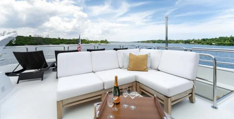 a white couch with a glass of wine on a table with a bottle of wine on it aboard ZEPHYR Yacht for Charter