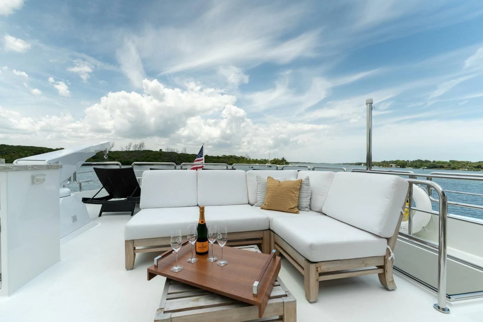 a glass bottle of wine on a white couch on a deck overlooking a body of water aboard ZEPHYR Yacht for Charter
