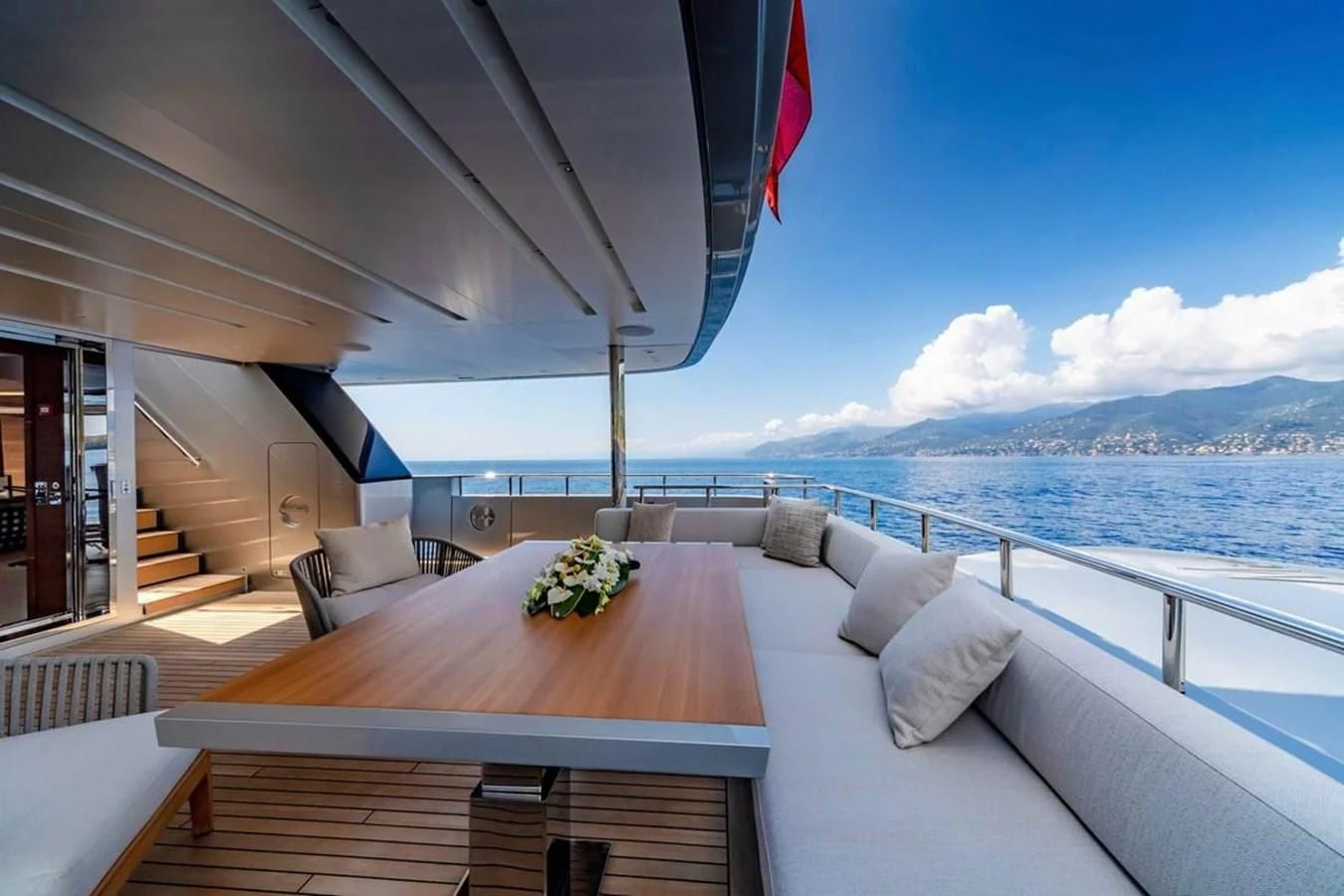 a large white bed with a wood table and chairs on it aboard LADY A Yacht for Sale