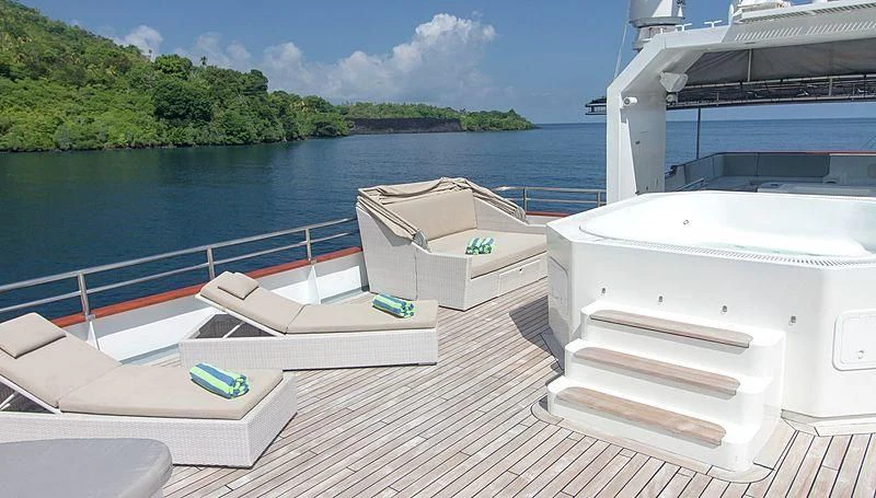 a deck with white lounge chairs on it and a body of water in the background aboard SALILA Yacht for Sale