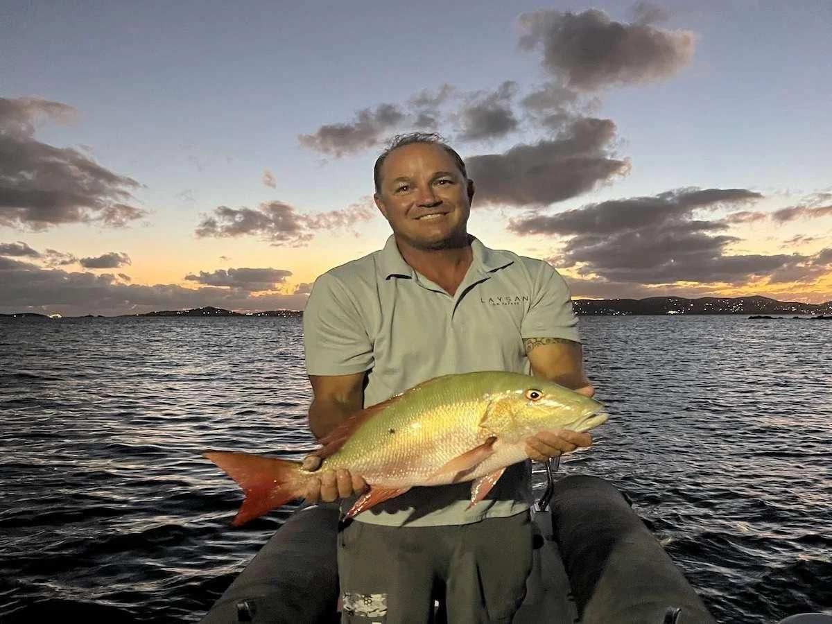 a man holding a fish aboard LAYSAN Yacht for Sale