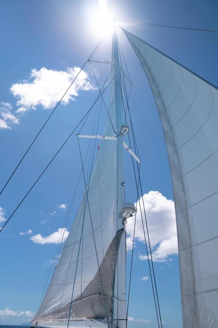 a large white boat with a blue sky and clouds aboard LAYSAN Yacht for Sale