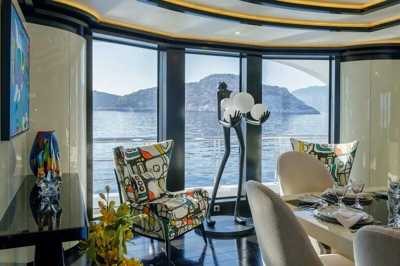 a room with a table chairs and a window with a painting aboard LADY VERA Yacht for Sale