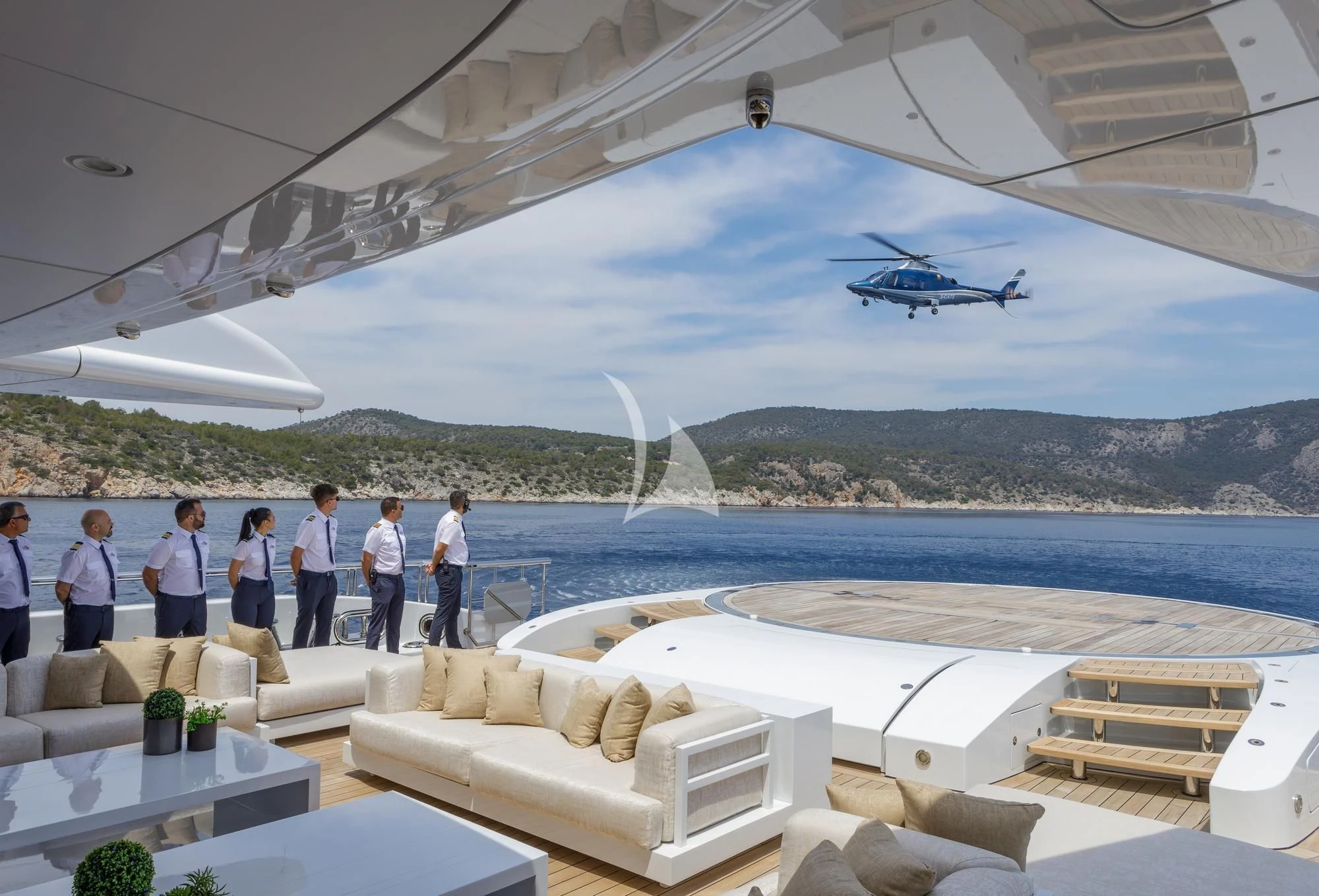 a group of people standing on a deck looking at a helicopter flying over water aboard LADY VERA Yacht for Sale
