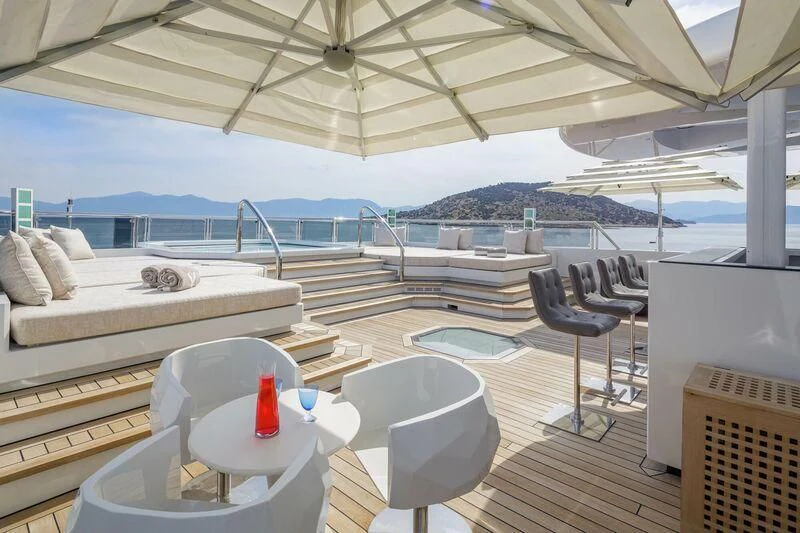 a deck with a view of the ocean and a large boat aboard LADY VERA Yacht for Sale
