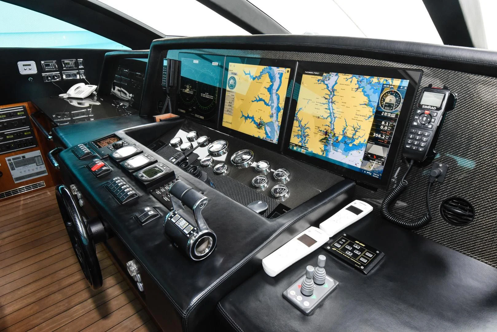 a black computer desk with multiple monitors and a few game controllers aboard DIABLO BLANCO Yacht for Sale