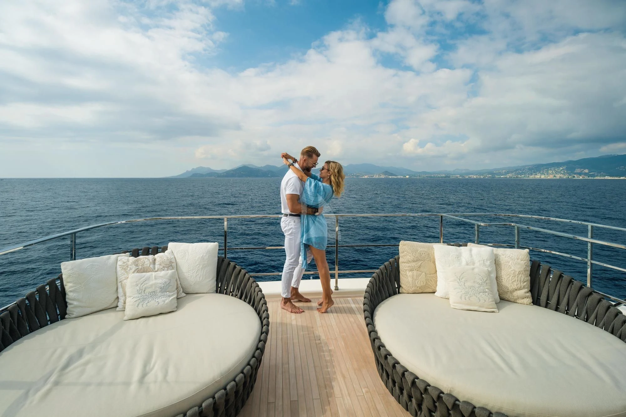 a man and woman standing on a dock with a body of water in the background aboard NEWAL Yacht for Sale
