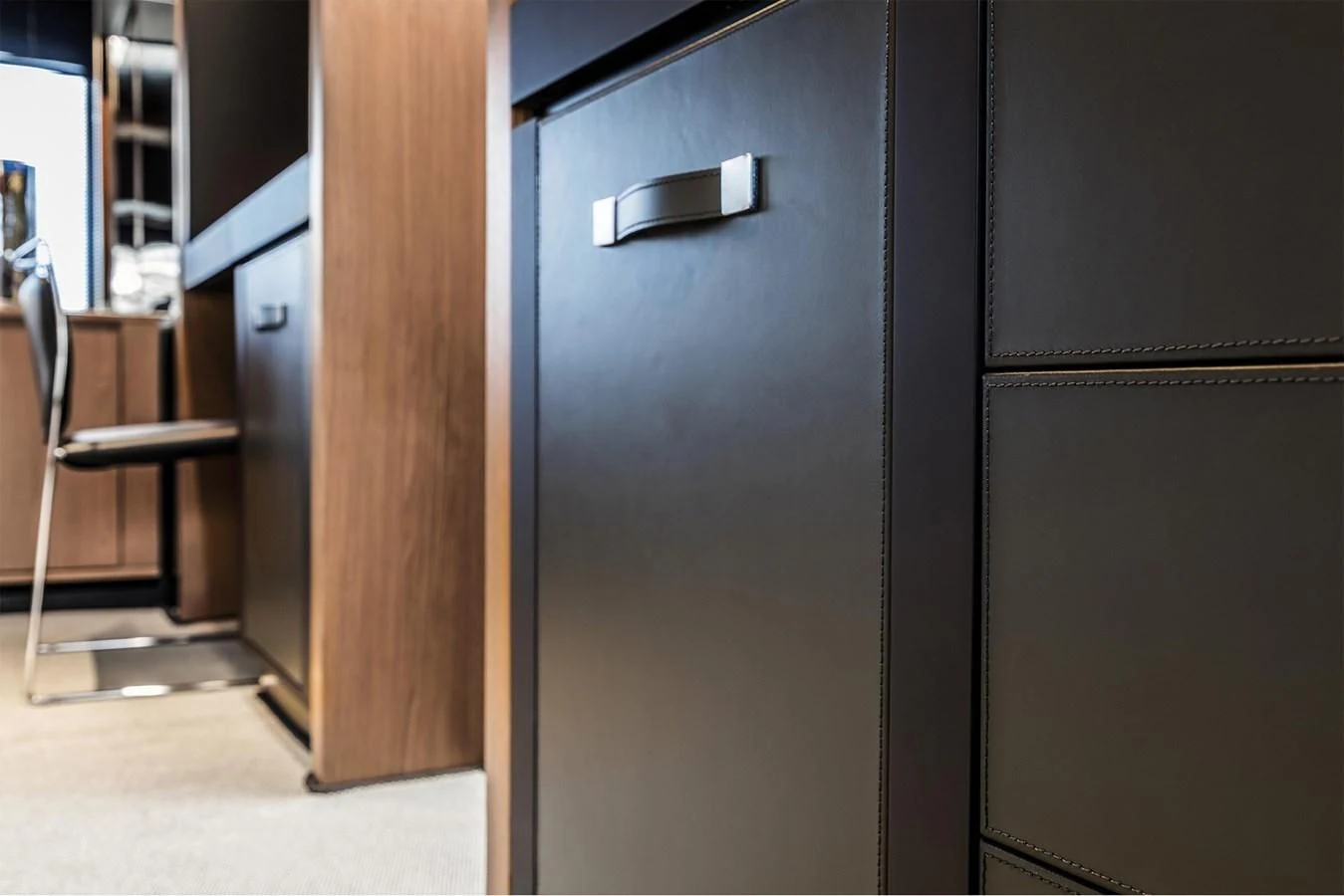 a black refrigerator next to a wooden door aboard RIVA 90' ARGO Yacht for Sale