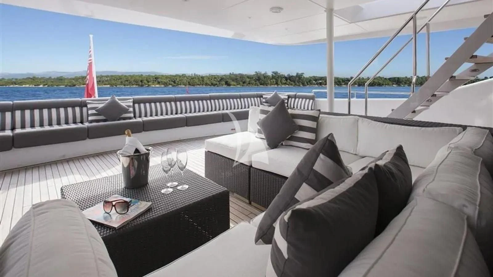 a large white lounge chair with a table and a glass of wine on a table with a bottle aboard BENIK Yacht for Charter