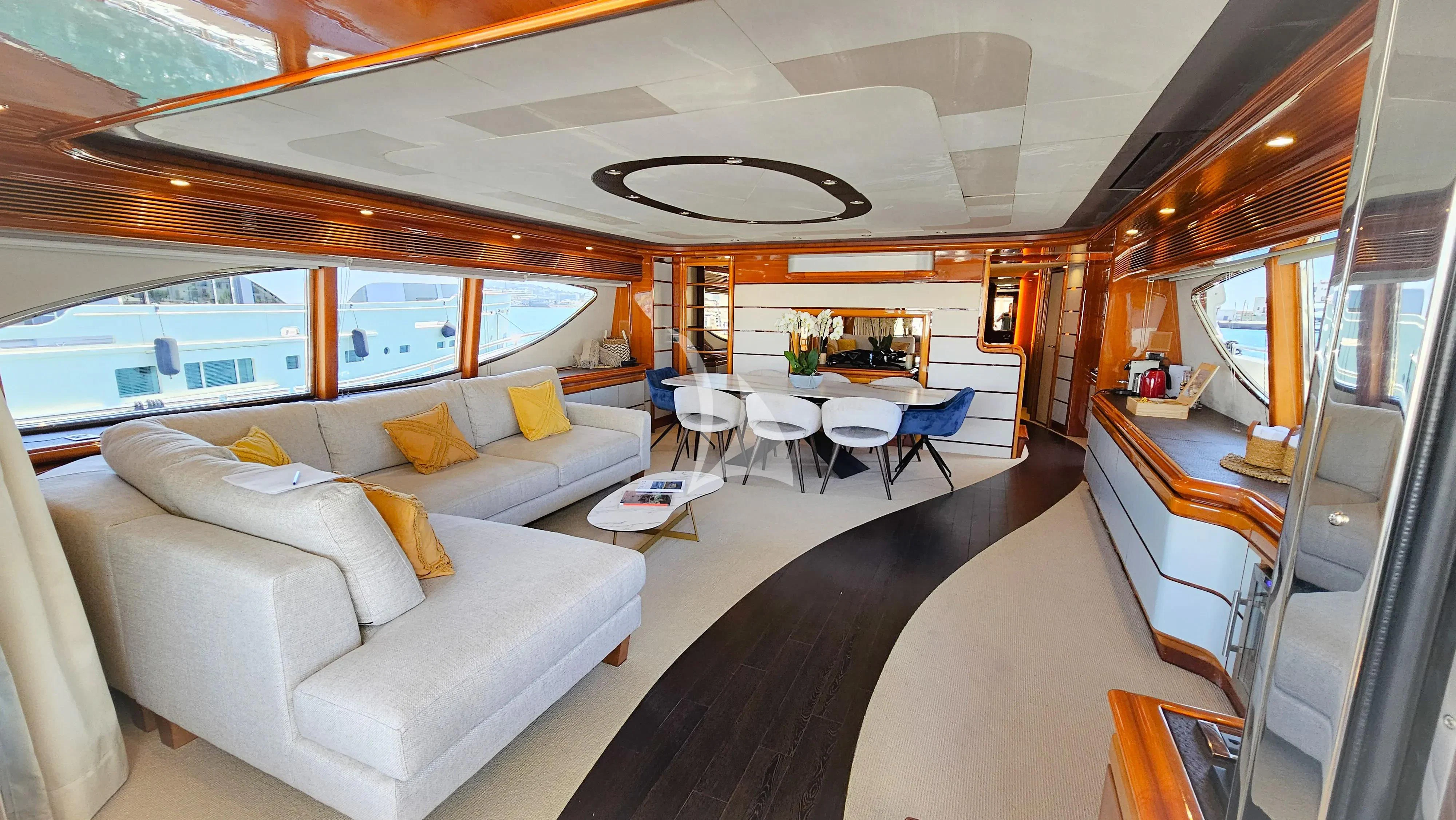a room with a couch and a table with chairs and a large window aboard YOLO TOO Yacht for Charter