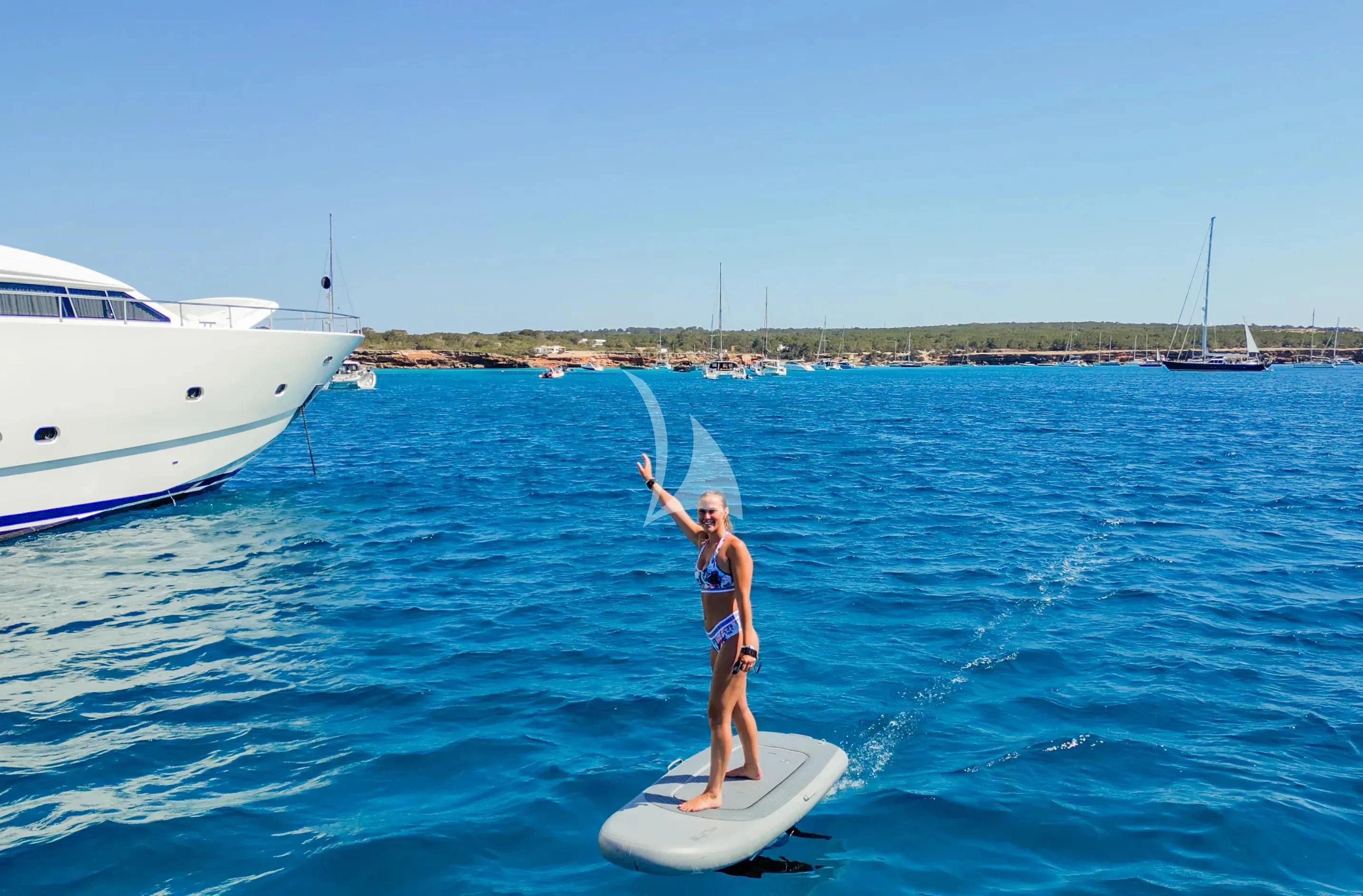 a man on a surfboard holding a pole and a fishing pole aboard YOLO TOO Yacht for Charter