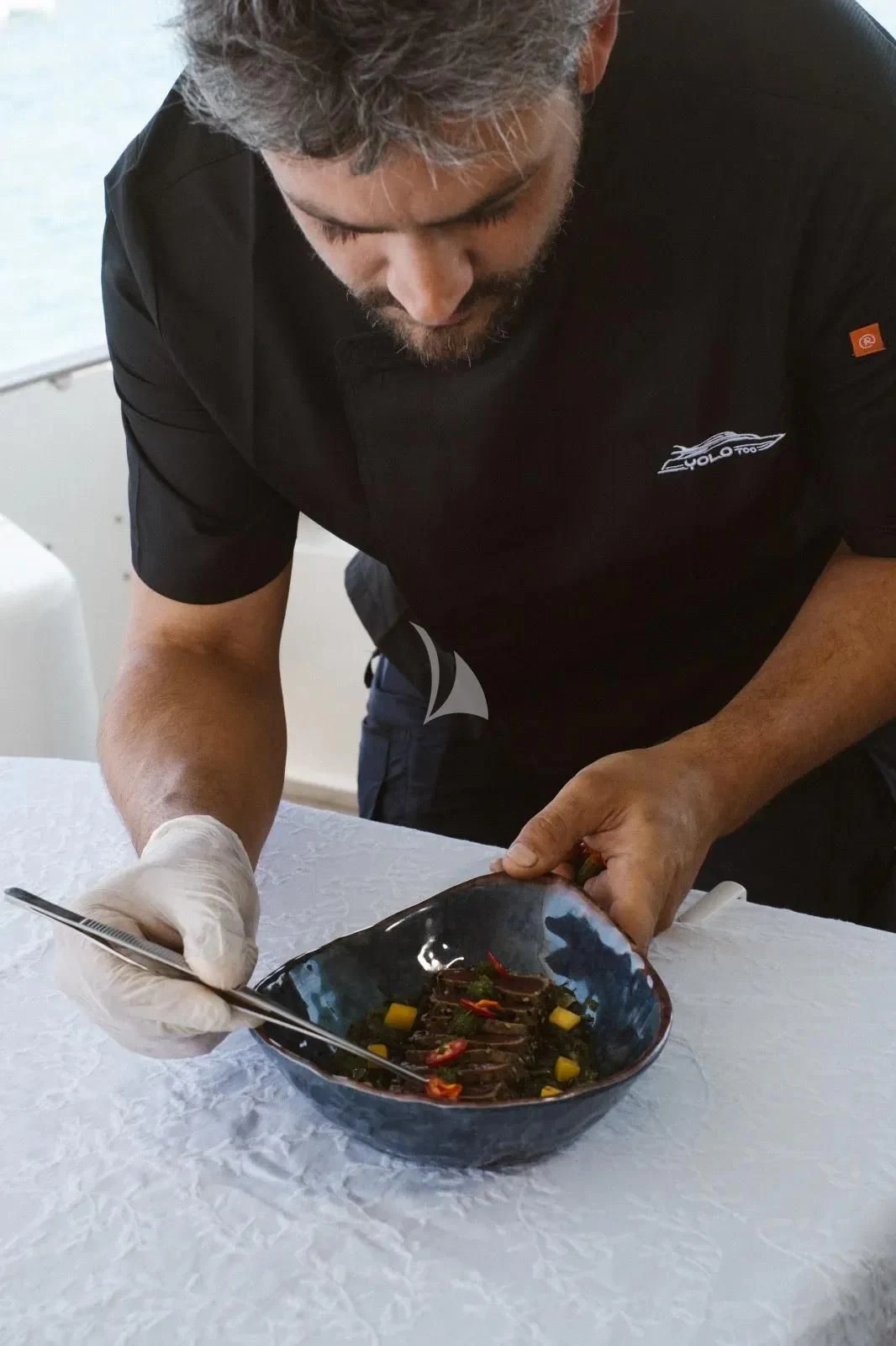 a man cutting food aboard YOLO TOO Yacht for Charter