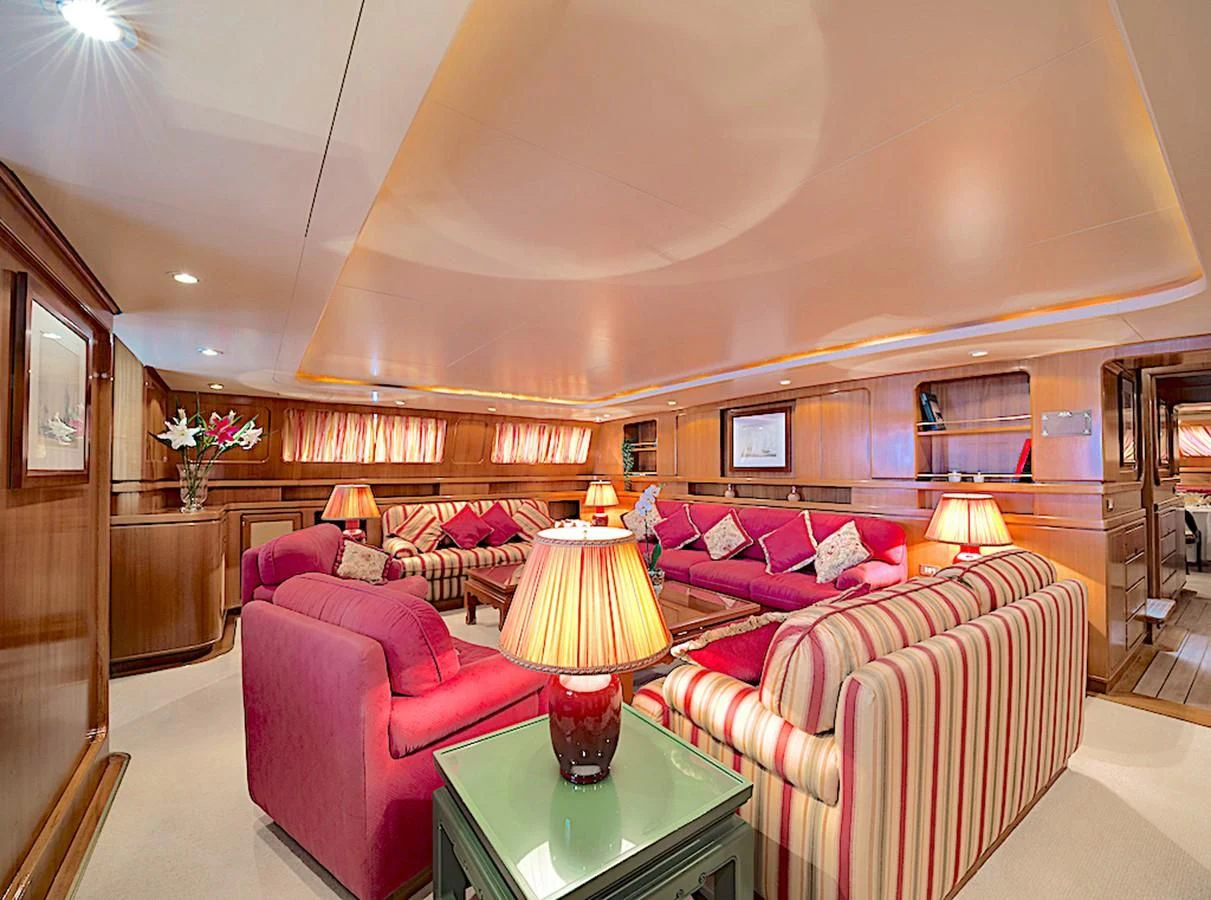 a living room with red couches aboard TAMARITA Yacht for Sale