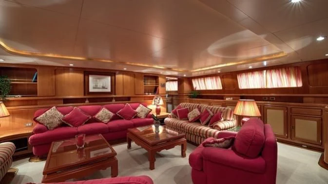 a living room with red couches and a coffee table aboard TAMARITA Yacht for Sale