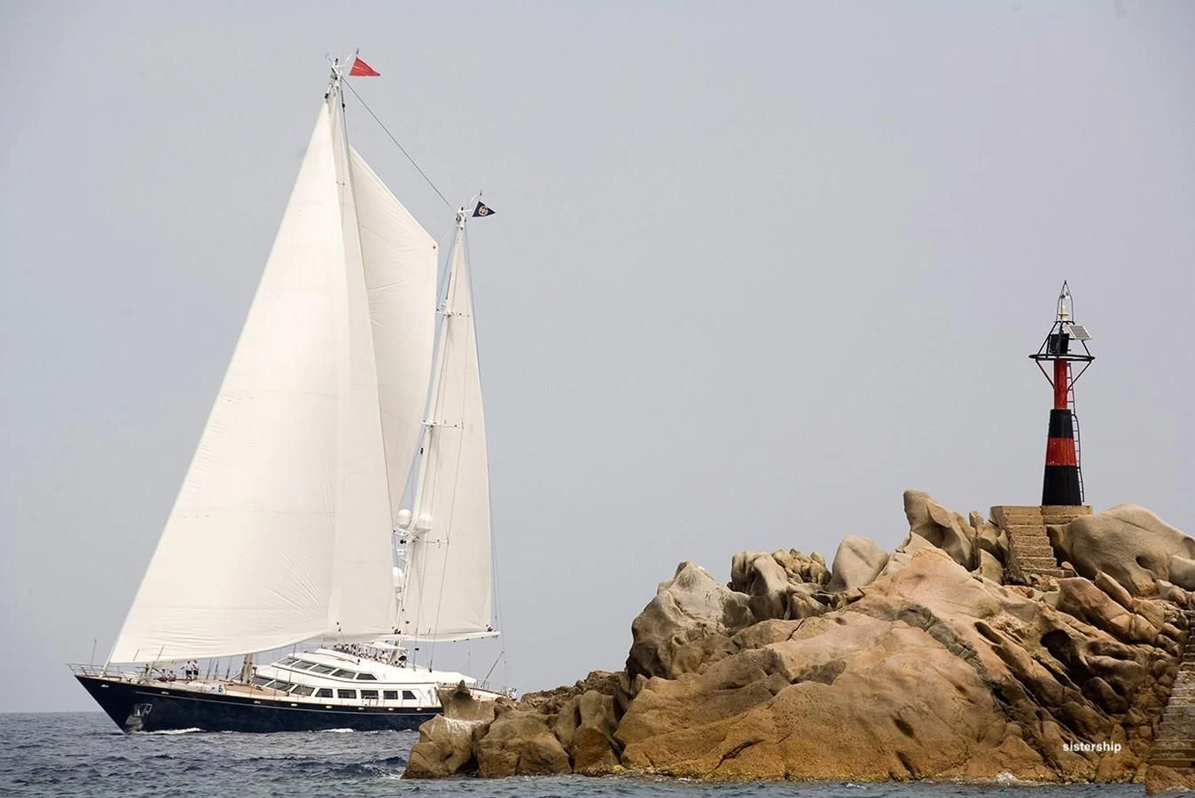 a sailboat and a lighthouse on a rocky beach aboard TAMARITA Yacht for Sale
