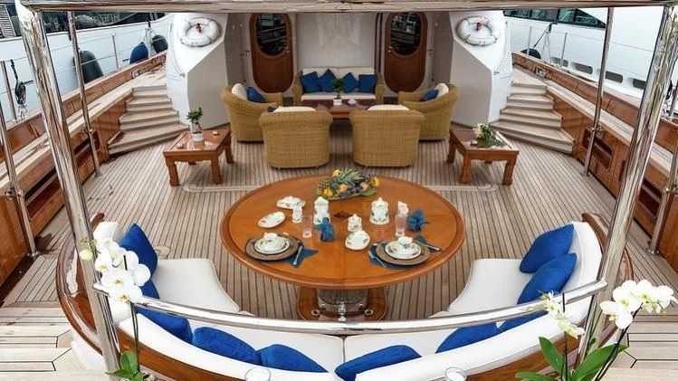 a large living room with a table and chairs aboard TAMARITA Yacht for Sale
