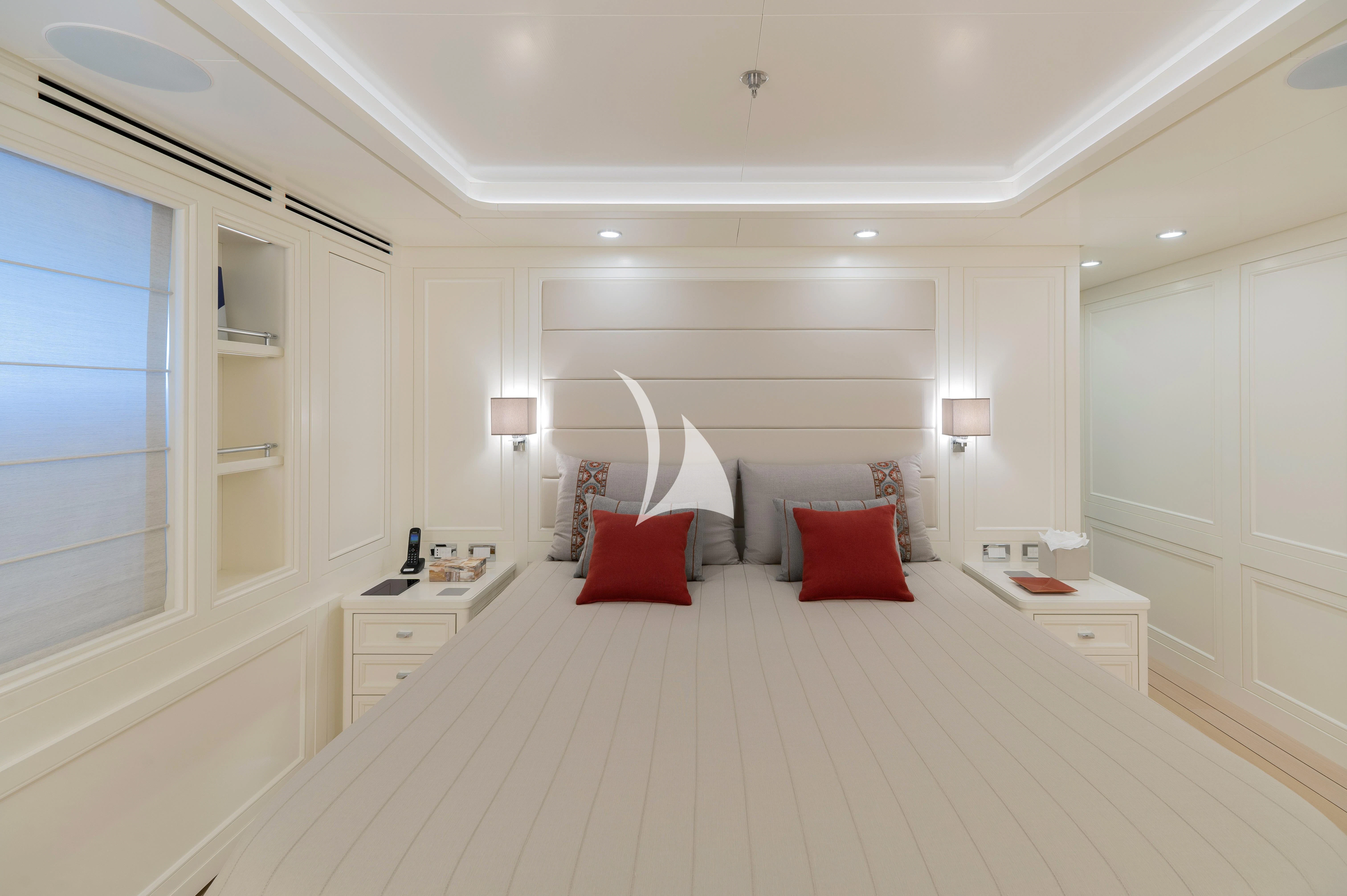 a large white bedroom with red pillows aboard BOJI Yacht for Sale