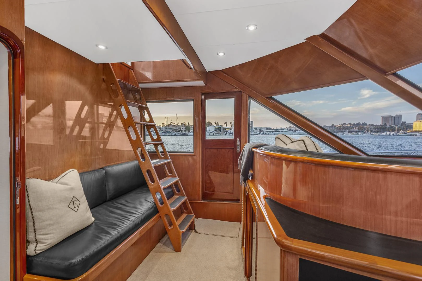 a bed and a couch in a room with a wood railing and a railing and a body of aboard EL ENCANTO Yacht for Sale