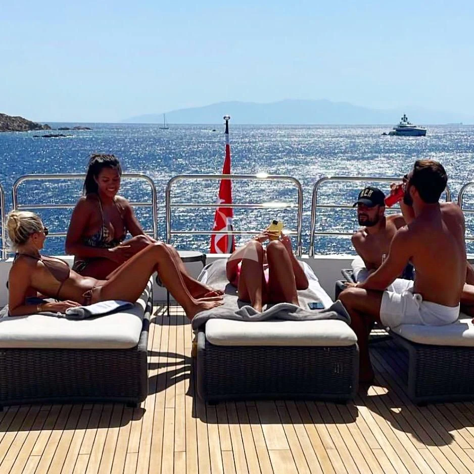a group of people sitting on a bench on a beach aboard ANYA Yacht for Sale