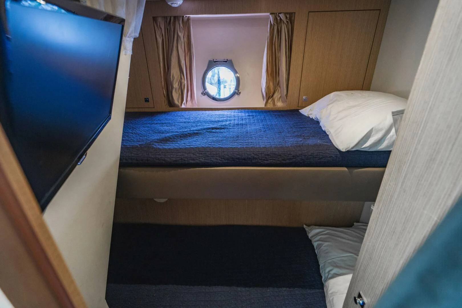 a bed with a blue sheet aboard KUDU Yacht for Sale