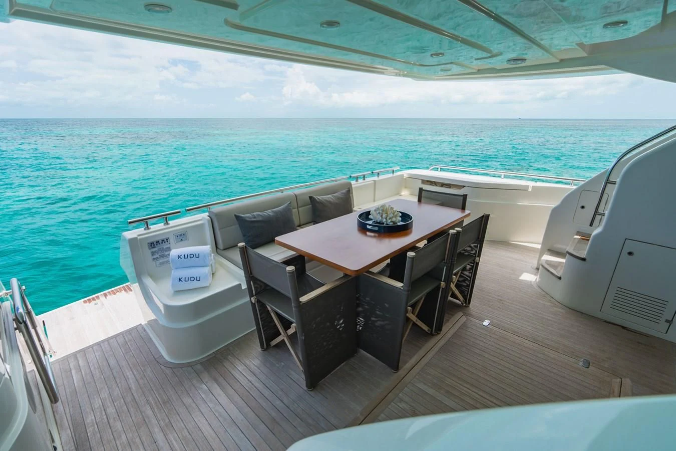 a table and chairs on a deck overlooking the ocean aboard KUDU Yacht for Sale