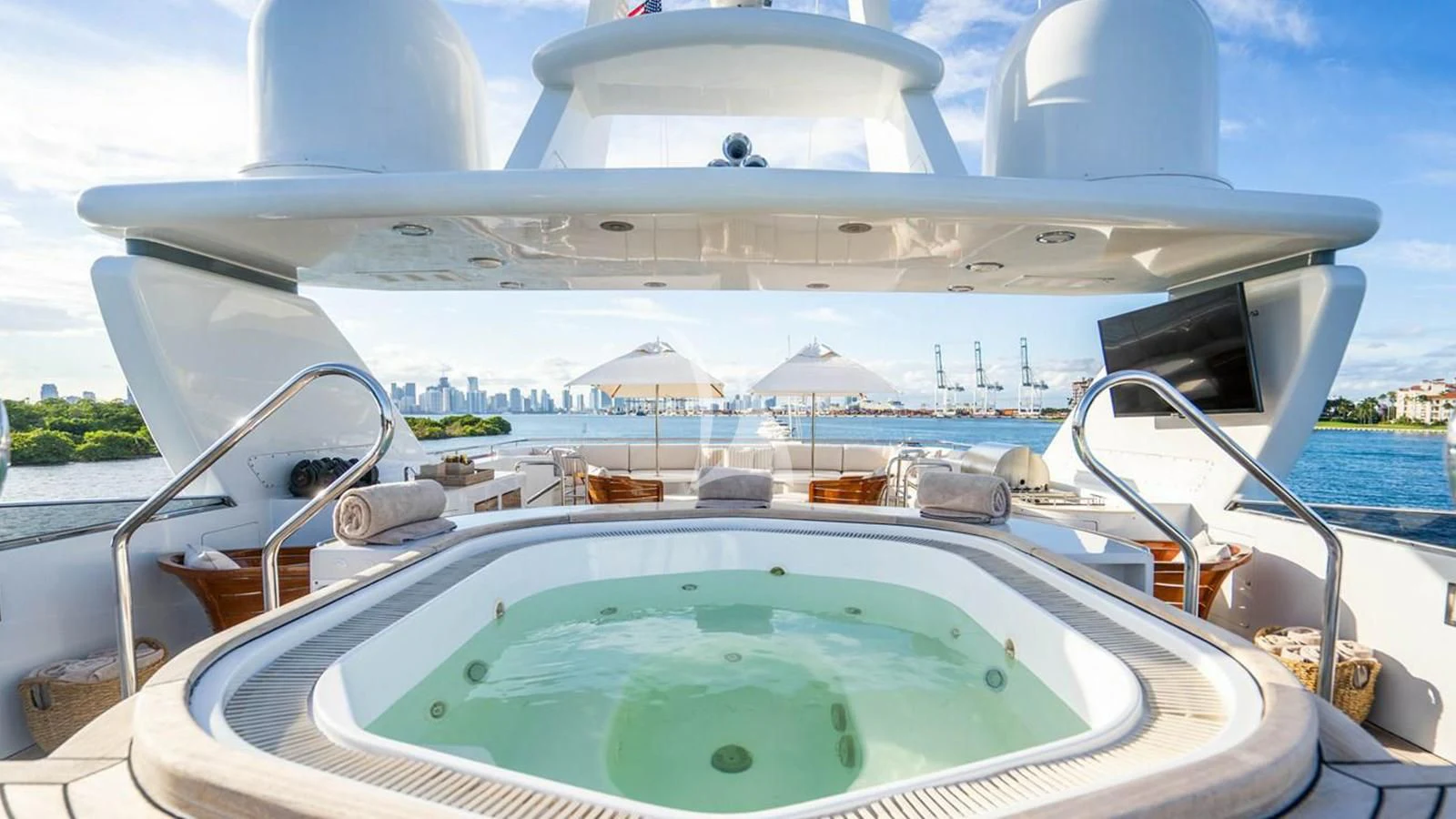 a white boat with a blue water pool and a white building in the background aboard ARTEMISEA Yacht for Sale