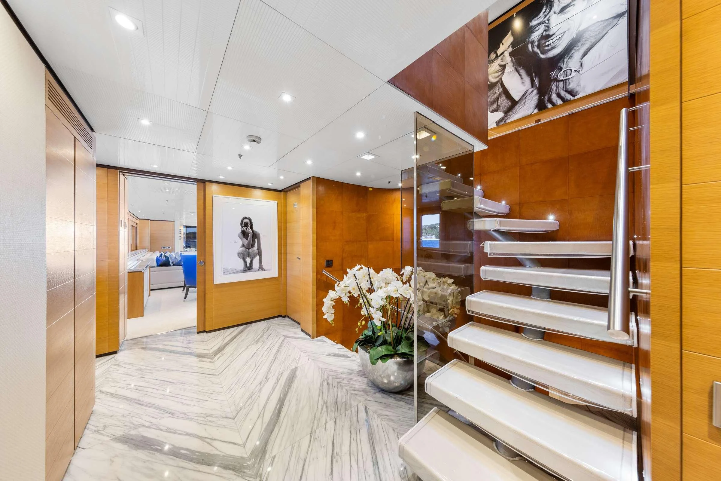 a modern looking room with a large staircase and white flowers aboard MISCHIEF Yacht for Sale
