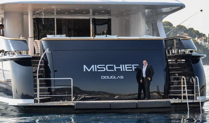a person in a suit standing on a boat aboard MISCHIEF Yacht for Sale