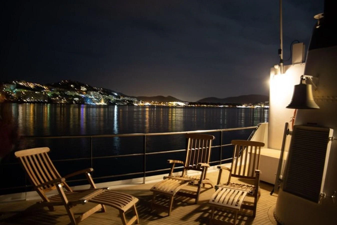 a deck with chairs and a view of a city at night aboard SPIRIT OF GINETTE Yacht for Sale