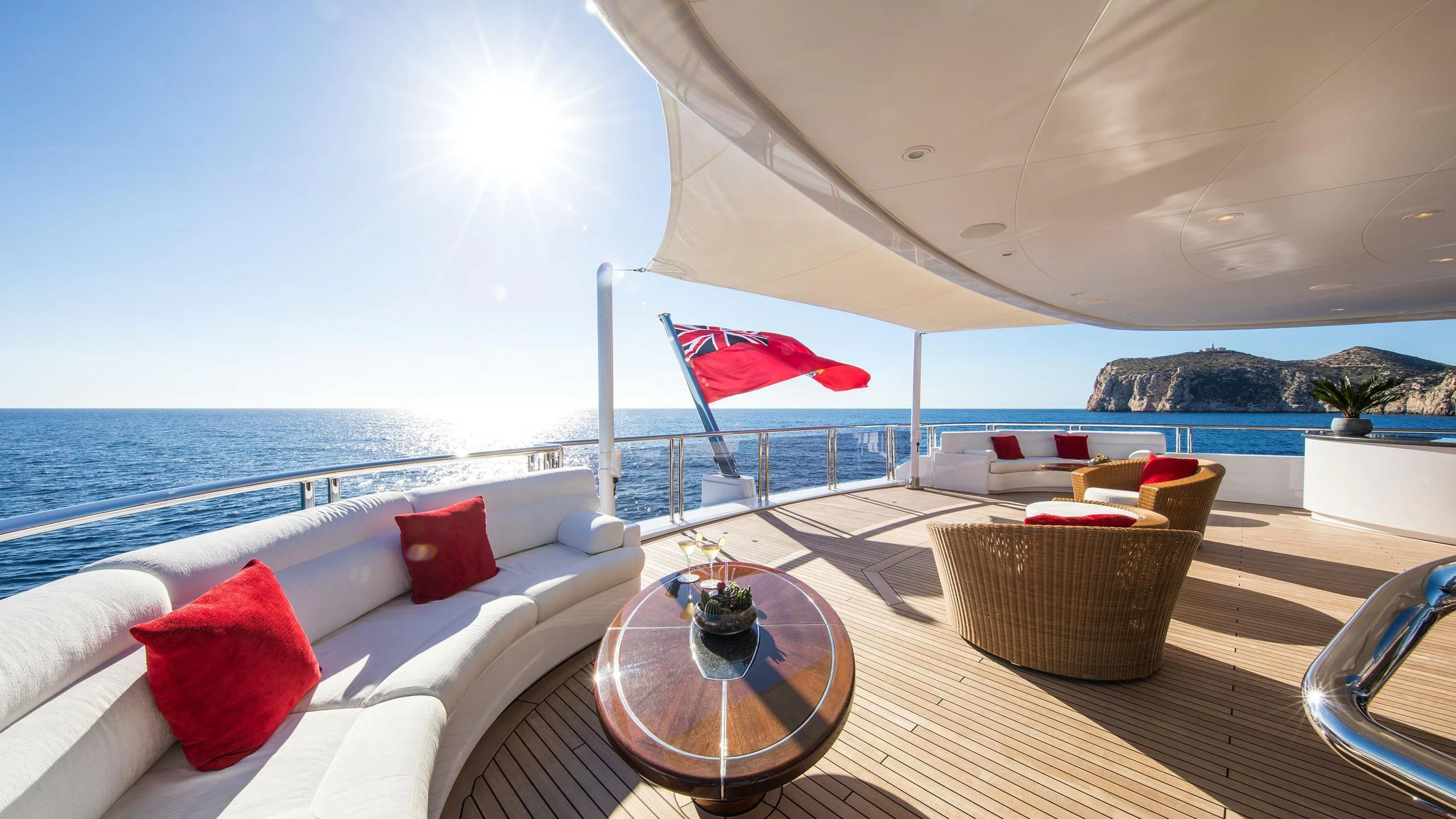 a large white lounge chair on a deck overlooking a beach aboard EMINENCE Yacht for Sale
