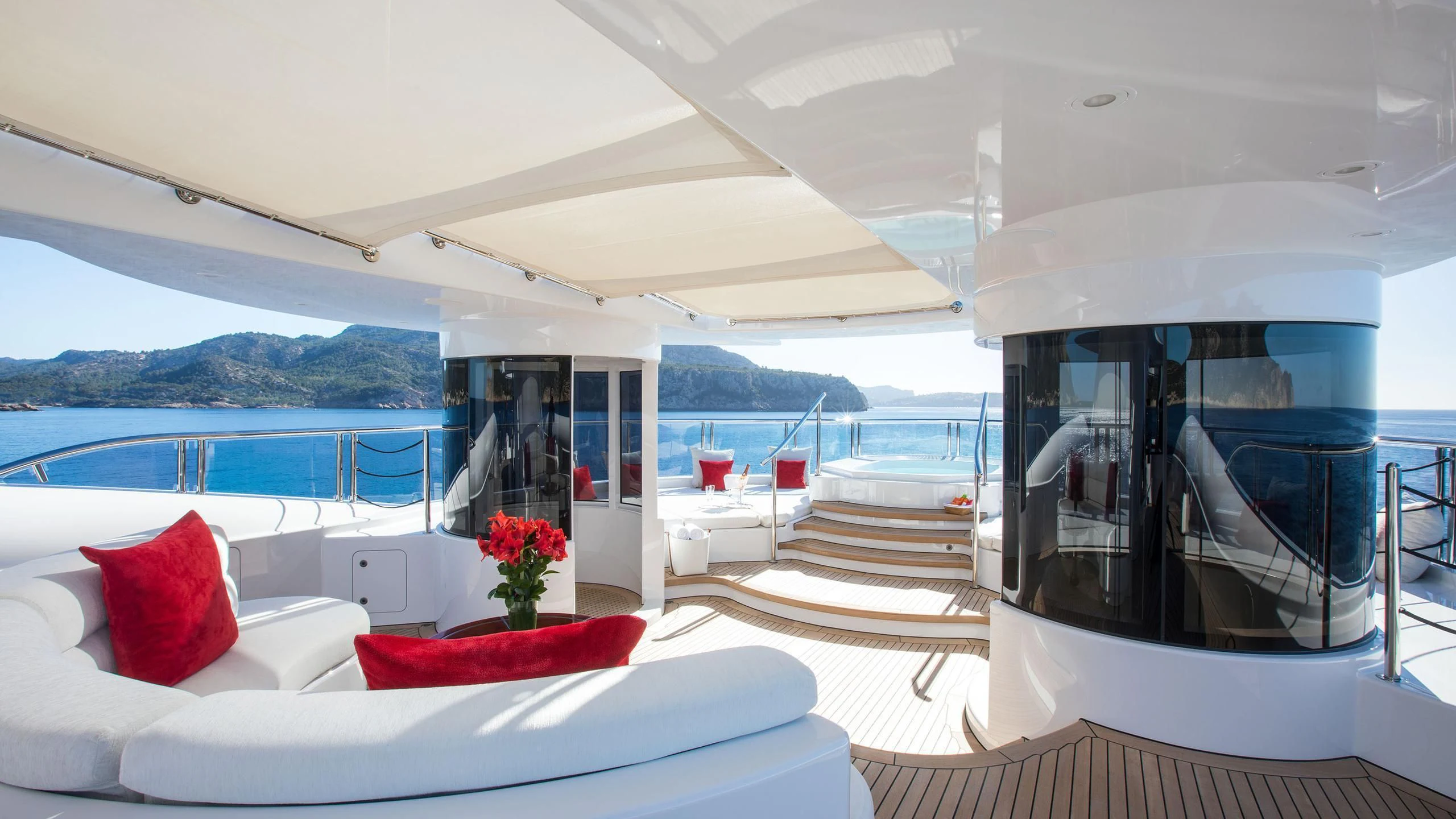 a room with a bed and a table and a view of the water aboard EMINENCE Yacht for Sale
