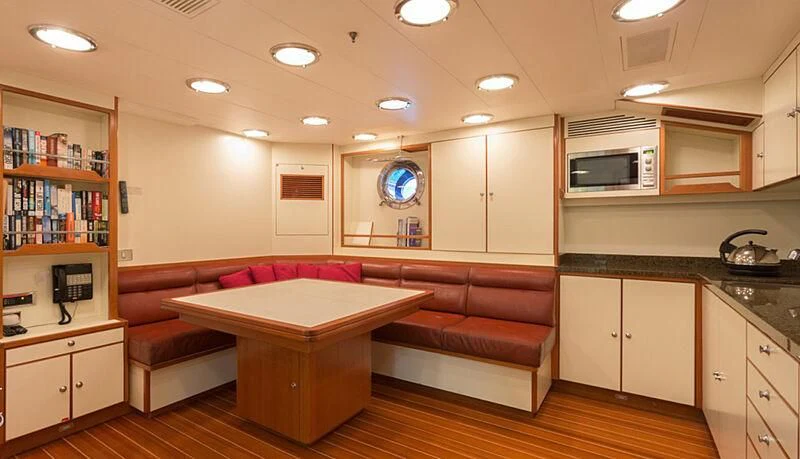 a kitchen with a table and a couch aboard BURRASCA Yacht for Sale