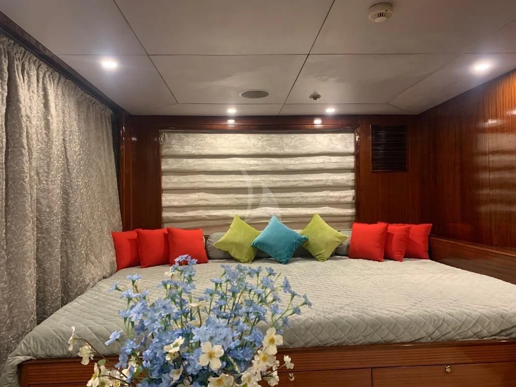 a bed with pillows and a flower arrangement in a room aboard ASHENA Yacht for Charter