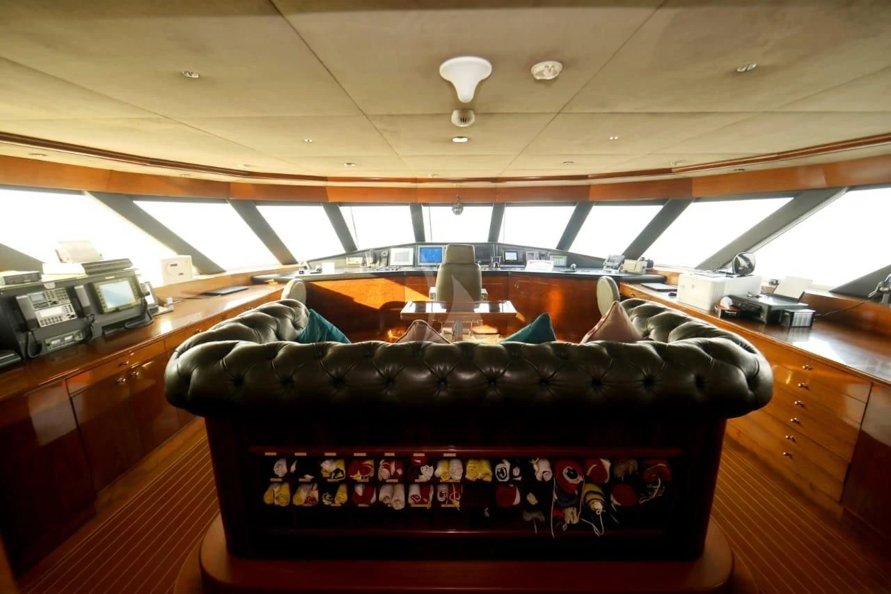 a black leather belt on a leather couch in a room with a wood floor and a ceiling fan aboard ASHENA Yacht for Charter