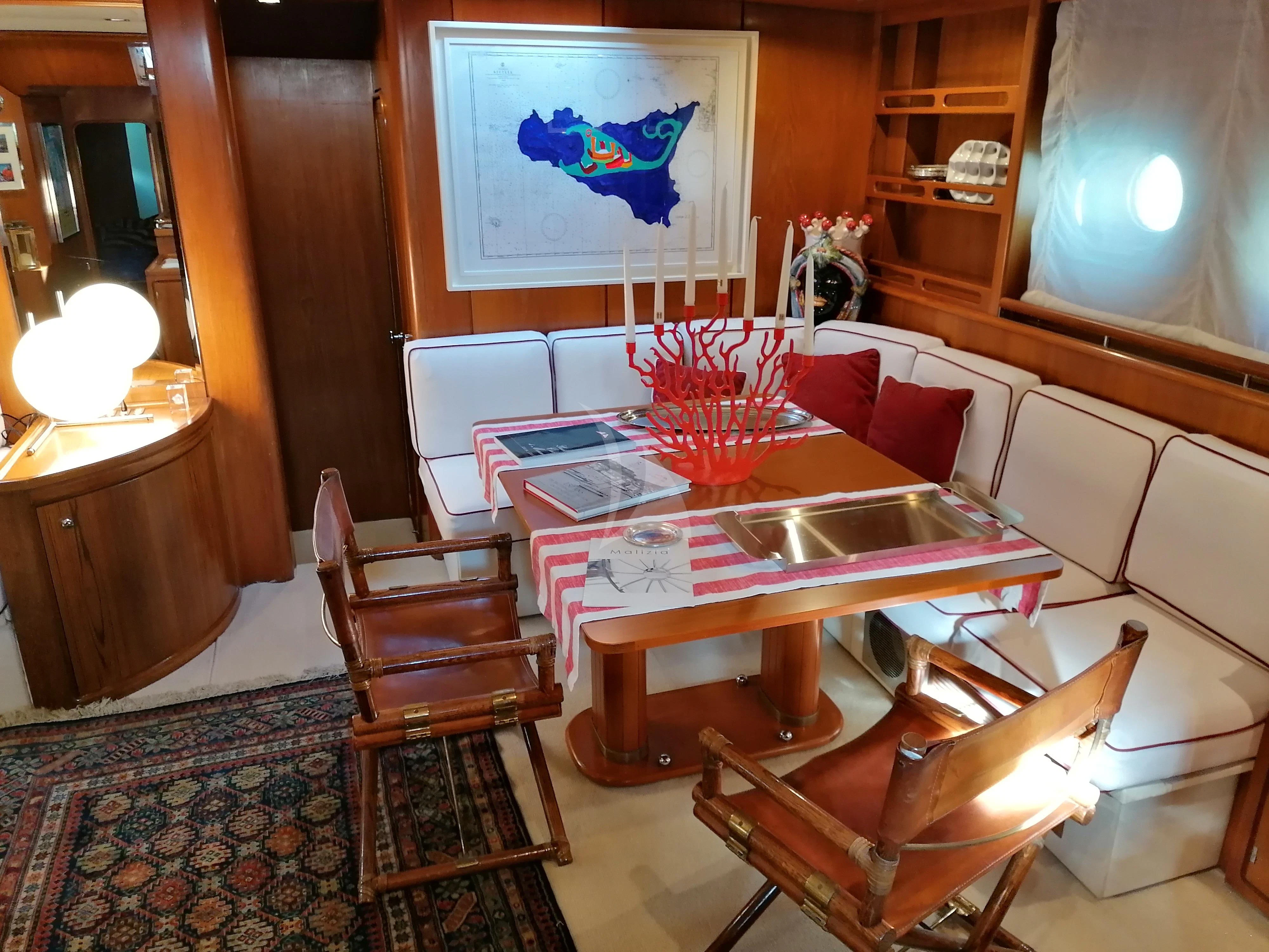 a table with chairs and a rug aboard MALIZIA Yacht for Sale