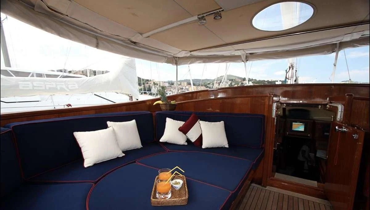 a blue couch with pillows and a table with a glass window aboard MALIZIA Yacht for Sale