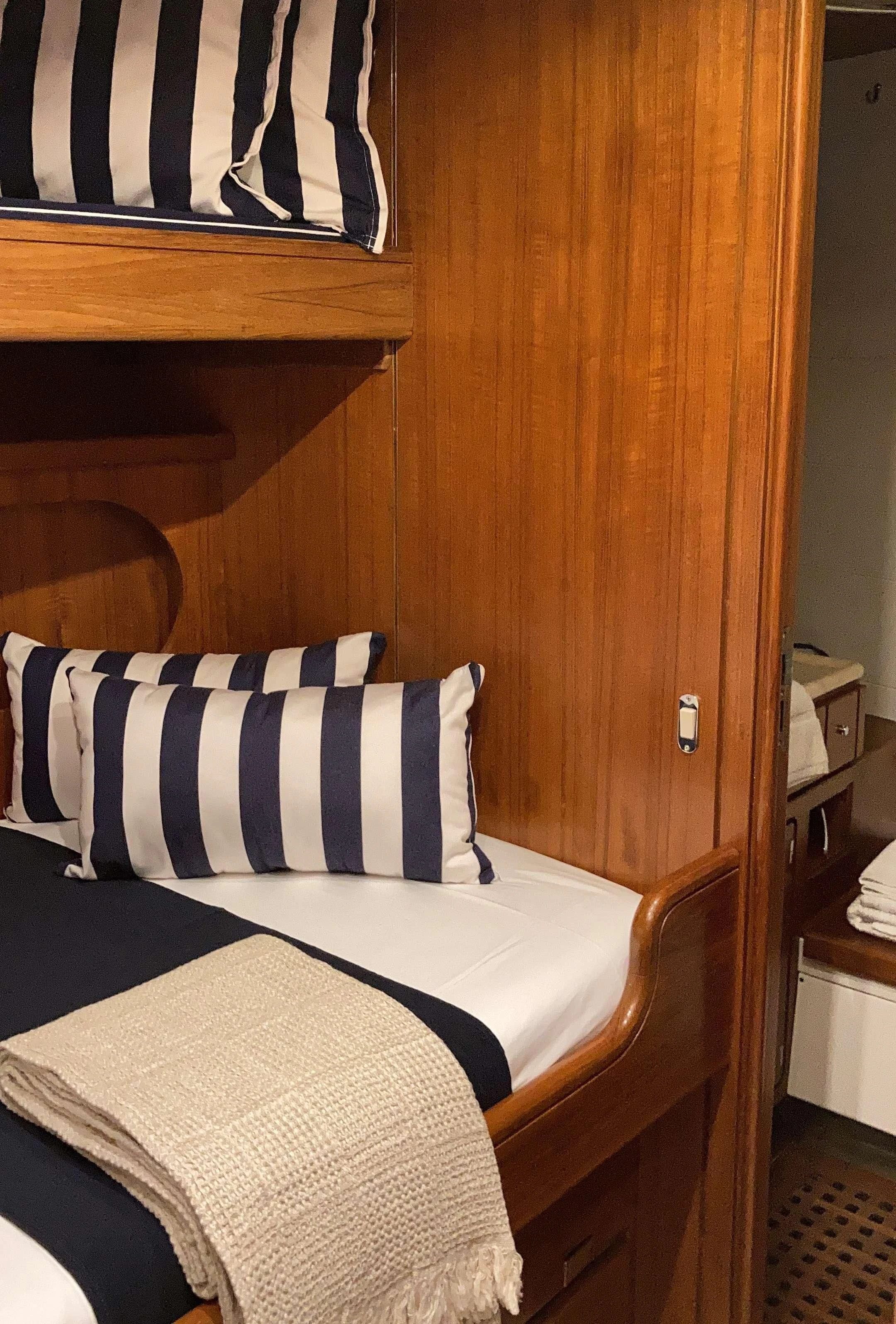 a bed with blue and white striped pillows aboard MALIZIA Yacht for Sale