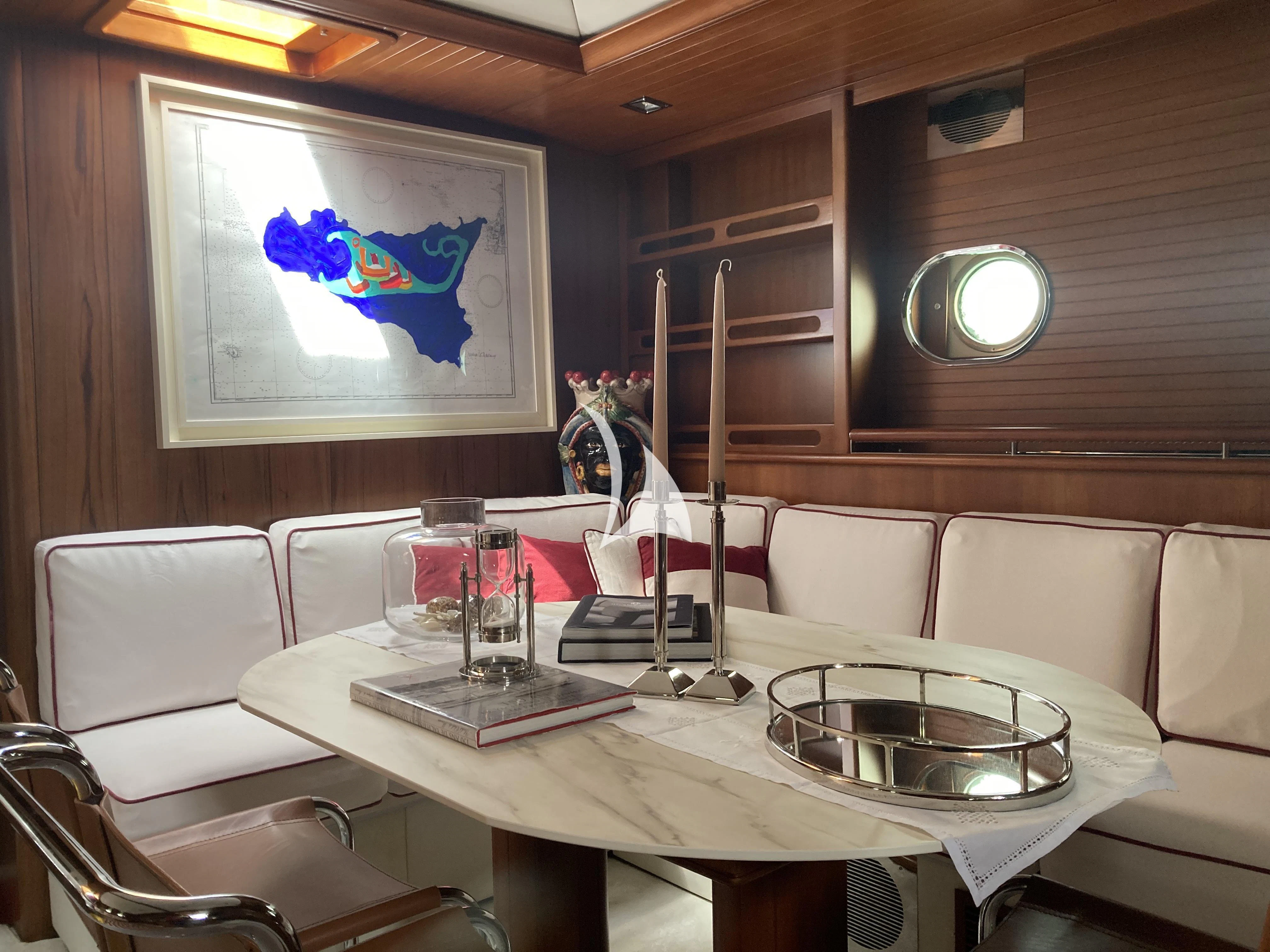 a table with chairs and a television aboard MALIZIA Yacht for Sale