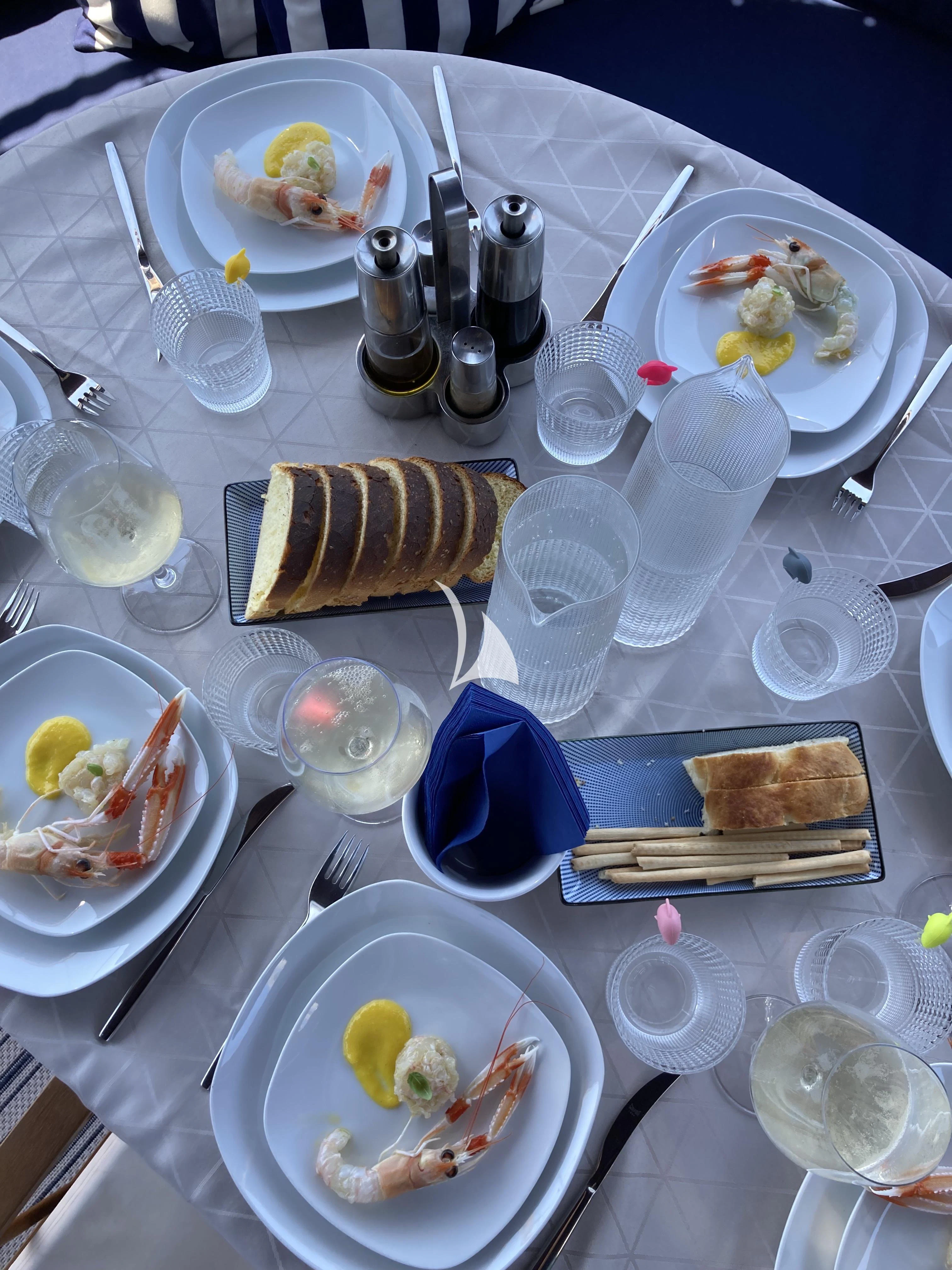 a table with plates of food and silverware aboard MALIZIA Yacht for Sale
