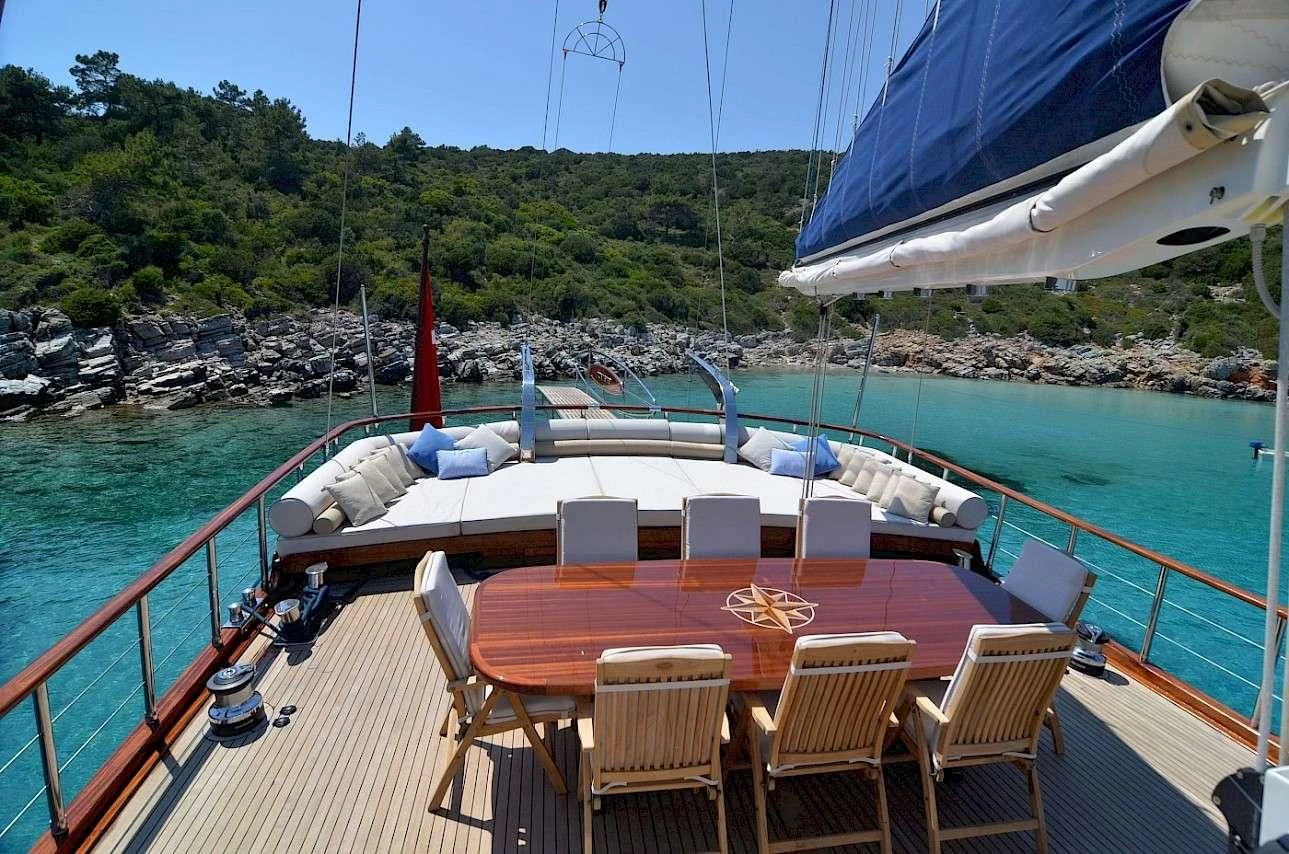a deck with chairs and tables on it next to a body of water aboard BLUE HEAVEN Yacht for Charter