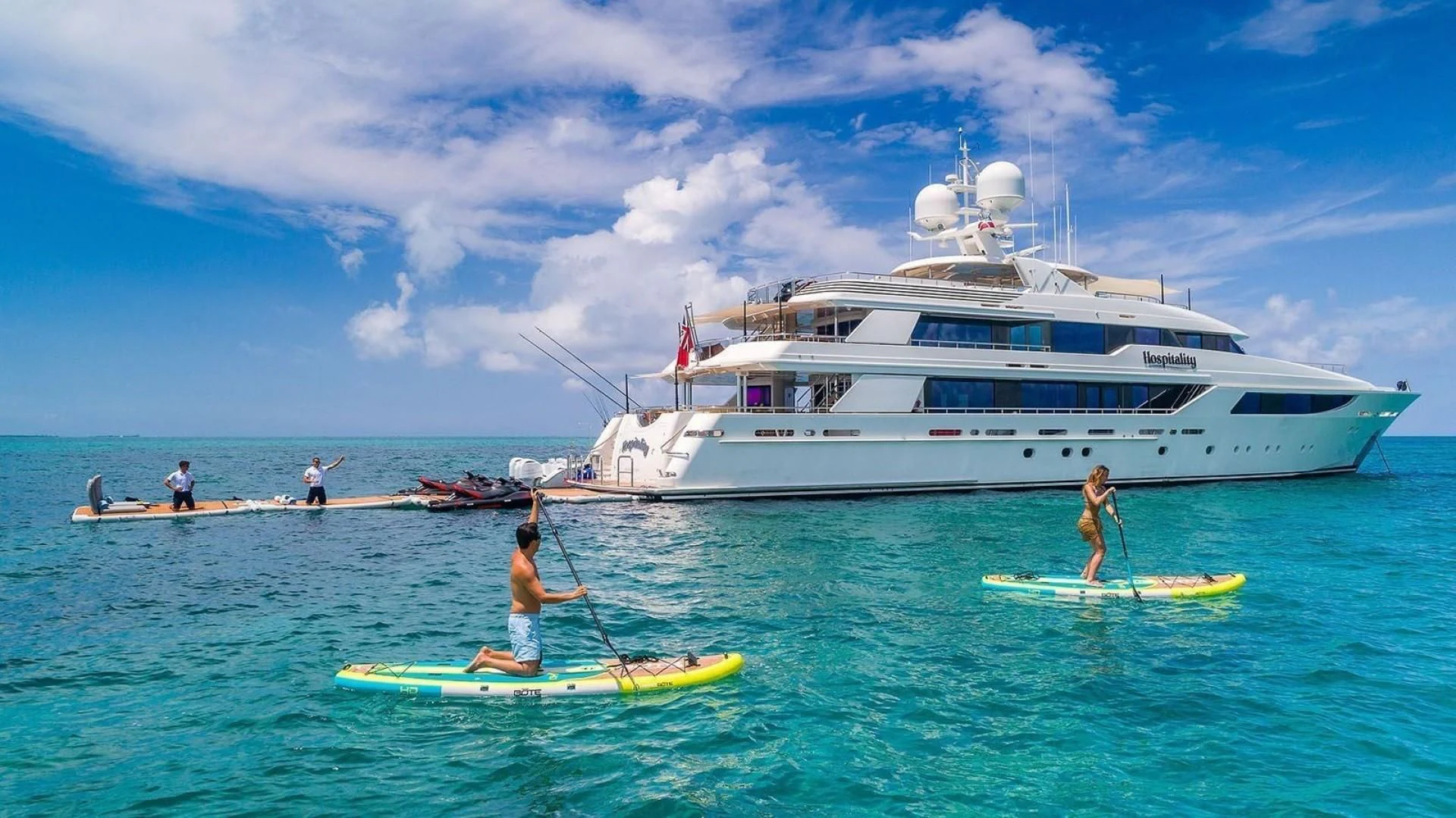 a group of people on a boat with a large white boat in the background aboard AS YOU WISH Yacht for Sale