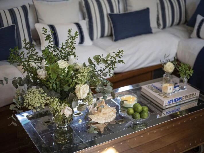 a table with flowers and a bottle of liquor on it aboard ALEXA OF LONDON Yacht for Sale