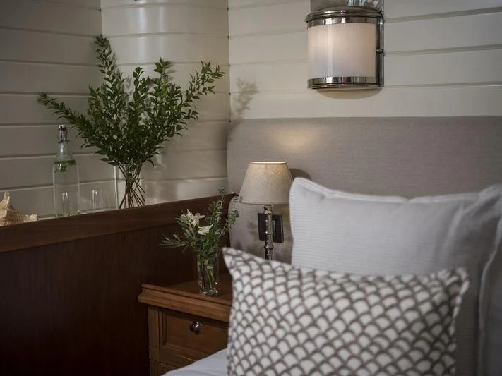 a white chair next to a lamp and a plant on a table aboard ALEXA OF LONDON Yacht for Sale