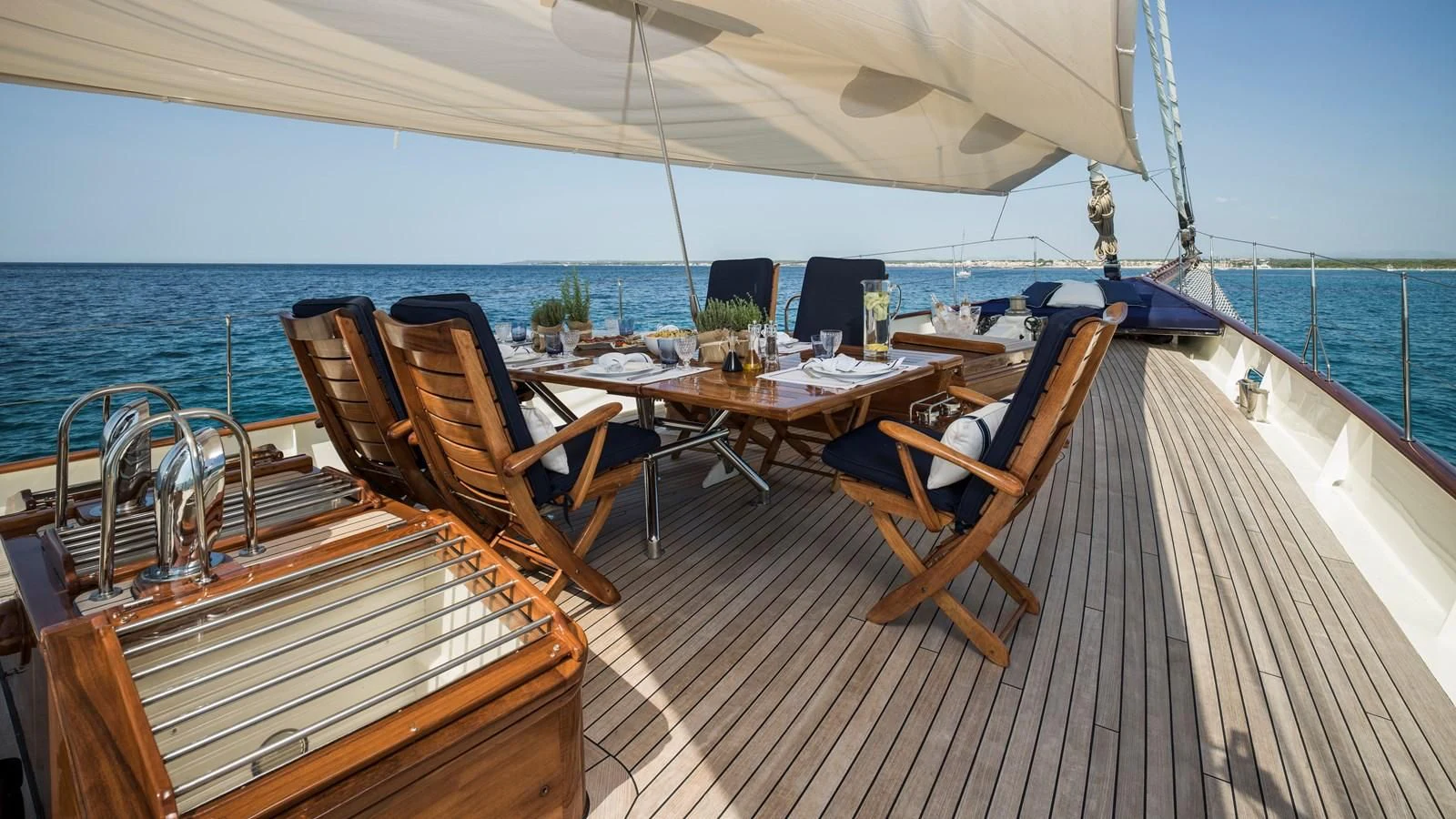 a deck with a table and chairs on it aboard ALEXA OF LONDON Yacht for Sale