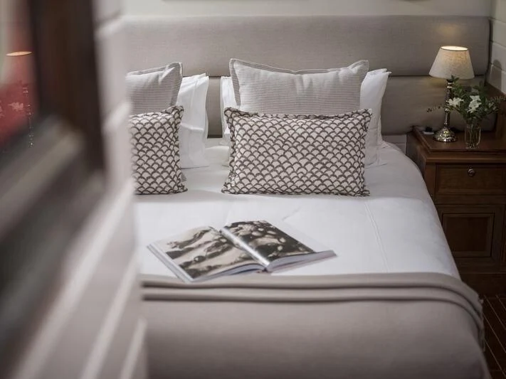 a bed with white sheets and pillows aboard ALEXA OF LONDON Yacht for Sale