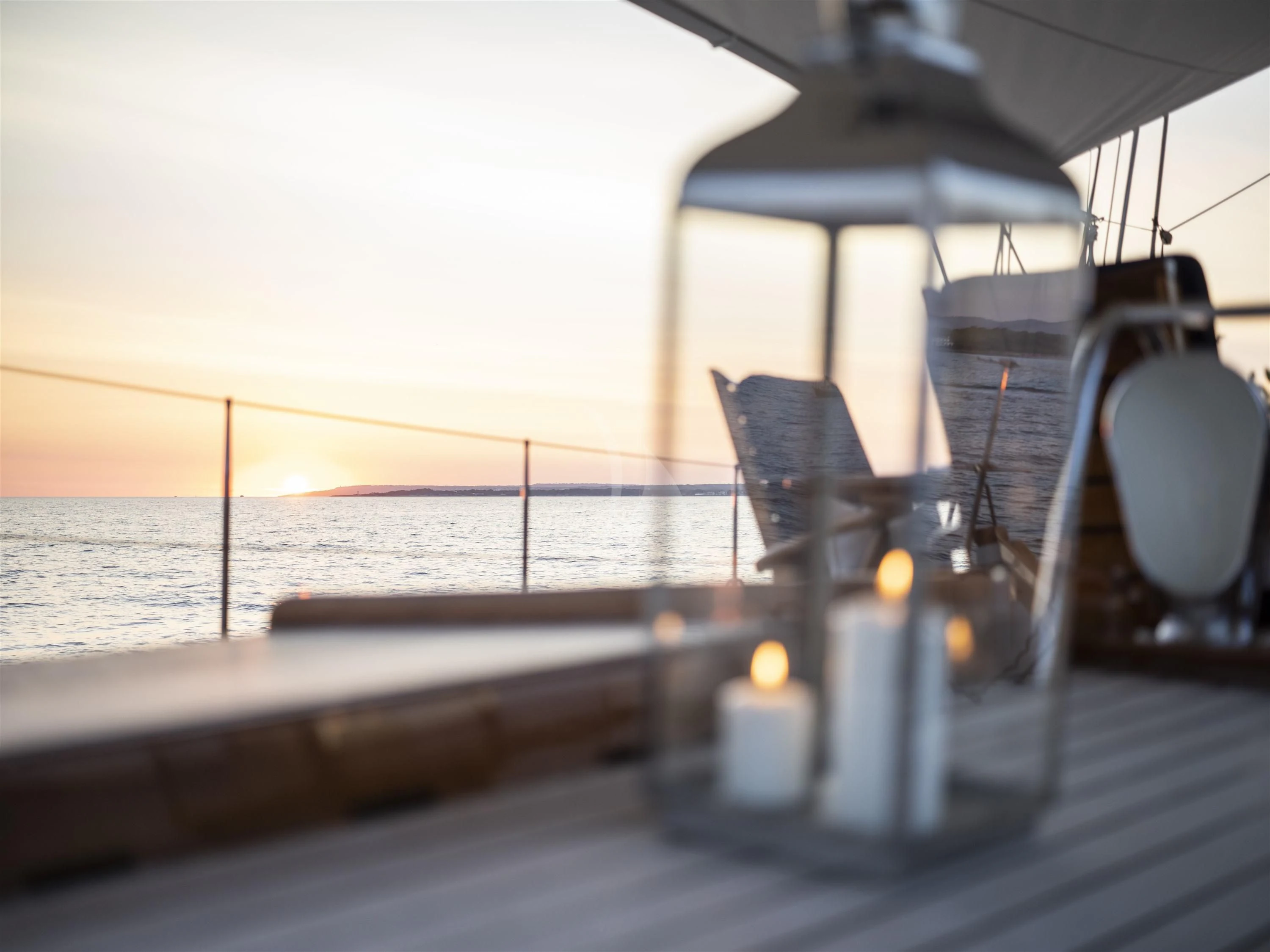 a deck with candles and a body of water in the background aboard ALEXA OF LONDON Yacht for Sale