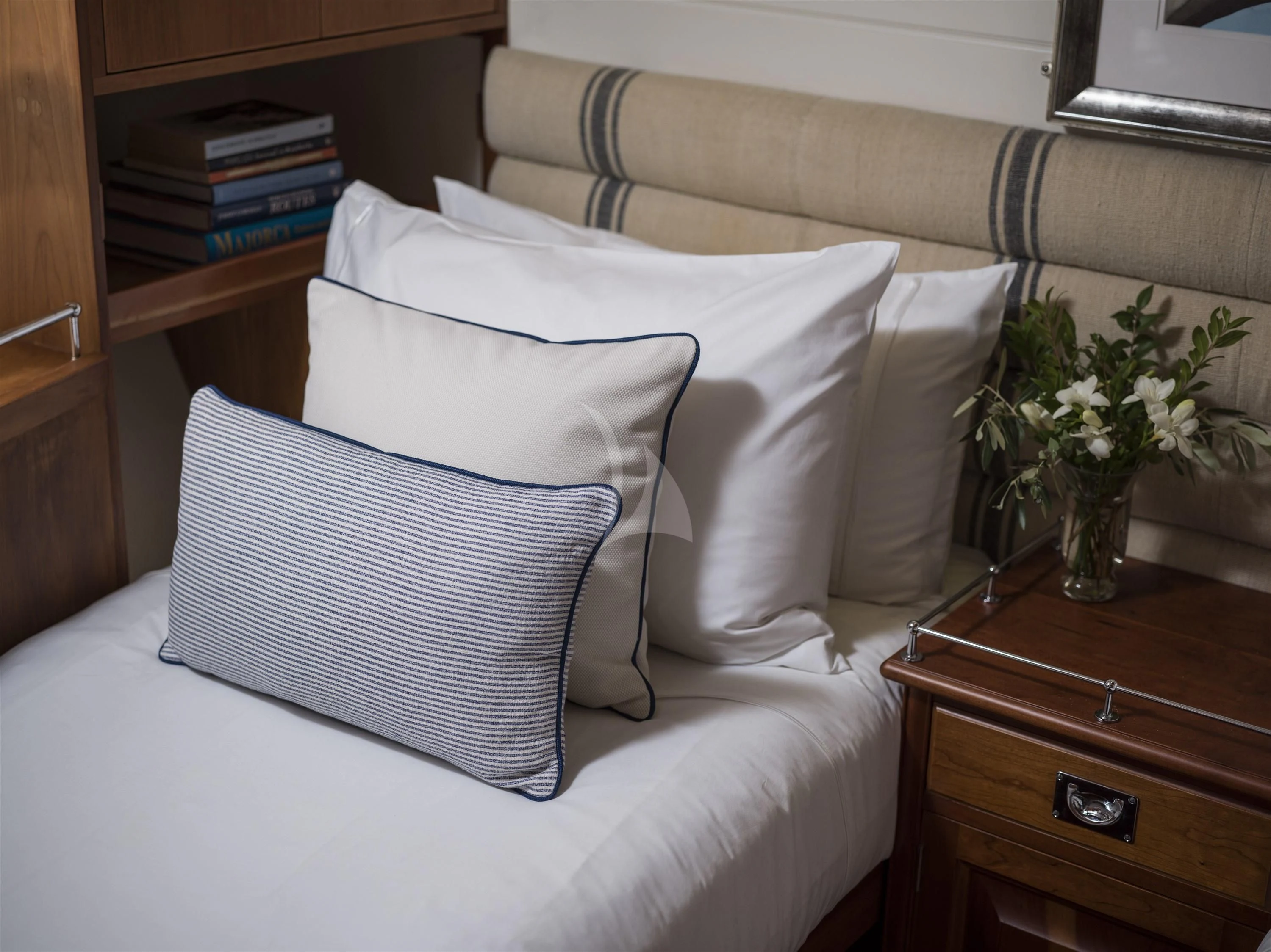 a bed with pillows and a vase of flowers aboard ALEXA OF LONDON Yacht for Sale