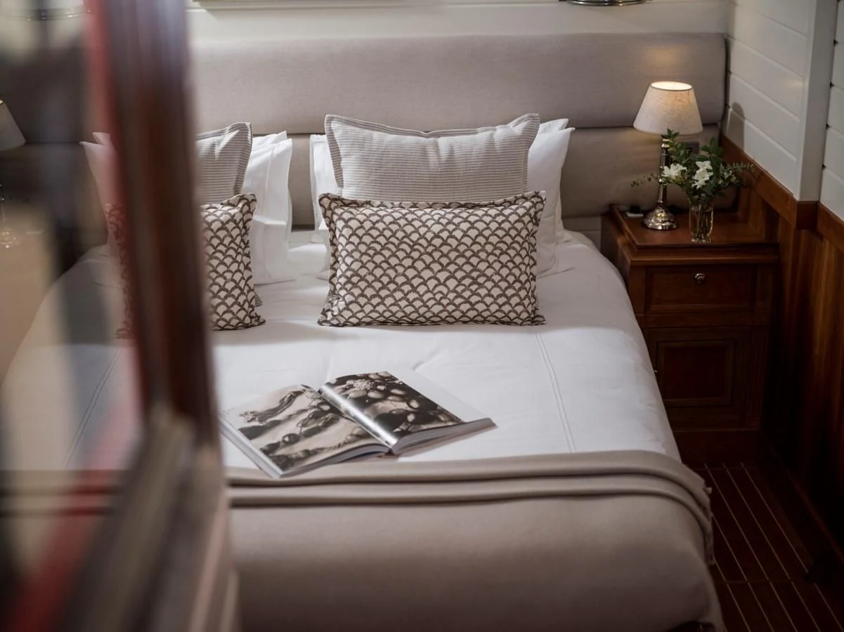 a bed with pillows and a book aboard ALEXA OF LONDON Yacht for Sale